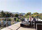 Businessman and businesswoman working on sunny luxury balcony patio sofa