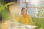 Pensive woman brainstorming, drawing at sunny kitchen table