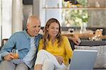 Couple relaxing, using laptop on living room sofa