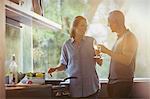 Couple toasting white wine glasses, cooking in kitchen