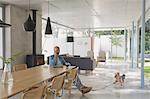 Dog running toward man talking on cell phone at home showcase interior dining table