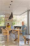 Man at dining table feeding dog