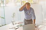 Male doctor standing at laptop in doctor’s office