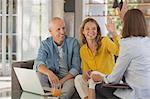 Happy couple high fiving financial advisor in living room