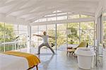 Mature man practicing yoga warrior 2 pose in luxury bedroom