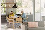 Mature couple working at laptop and eating at dining table