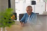 Mature man using digital tablet at dining table