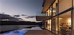 Tranquil modern luxury home showcase exterior with illuminated infinity pool and dusk ocean view