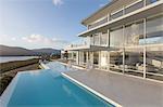 Sunny, tranquil modern luxury home showcase exterior with infinity pool