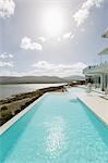 Sunny tranquil home showcase exterior infinity pool with ocean view