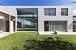 Sunny modern luxury home showcase exterior with grass courtyard