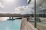 Sunny, tranquil modern luxury home showcase exterior with infinity pool and ocean view