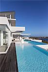 Sunny, tranquil modern luxury home showcase exterior with infinity pool