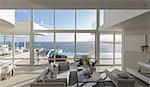Sunny, tranquil modern luxury home showcase interior living room with patio and ocean view