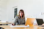 Woman sitting at desk in office working on laptop