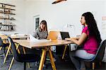 Colleagues at desk in office working on laptop