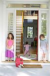 Boy and girl watching toddler crawling in house doorway