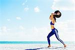 Young woman training, preparing to throw exercise ball on beach