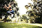 Young woman training, jumping between agility hurdles in park