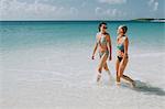Two mid adult sisters strolling in blue sea, Anguilla, Saint Martin, Caribbean