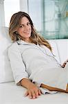 Woman smiling at camera in the couch listening to music