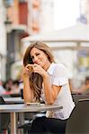 Portrait of a woman having a coffee outdoor smiling at camera