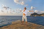 Man stretching his arms in a cliff in Ibiza