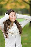 Portrait of a woman with closed eyes listening to music in the park in Autumn
