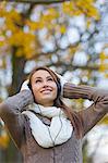 Portrait of a beautiful young woman listening to music in the park in Autumn