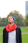 Young relaxed man standing in the park with hat