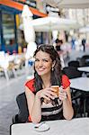 Portrait of a woman having a coffee outdoor smiling at camera