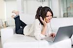 Beautiful brunette woman on a couch with computer and headphones