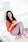 Pretty brunette woman having breakfast in bed