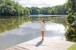 Pretty elegant woman stretching by a lake
