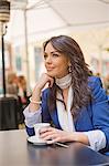 Portrait of a pretty brunette woman having a coffee outdoor smiling