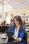 Portrait of a woman with tablet having a coffee outdoor