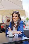 Portrait of a pretty brunette woman having a coffee outdoor smiling