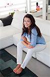 Portrait of a pretty brunette woman sitting on the sofa looking at camera