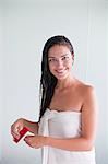 Brunette woman brushing her hair and smiling at camera