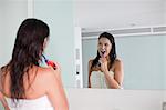 Brunette woman brushing her teeth in front of the mirror