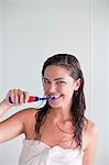 Brunette woman brushing her teeth looking at camera