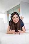 Pretty brunette woman listening to music lying on the Sofa