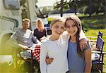 Portrait smiling sisters hugging outside sunny motor home