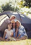 Happy family taking selfie with camera phone outside sunny campsite tent