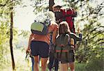 Family with backpacks hiking in sunny woods