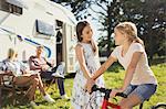 Sisters with bicycle outside sunny motor home