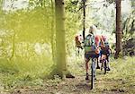 Family mountain biking on trail in woods