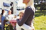 Mother and daughter hugging outside sunny motor home