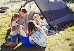 Family opening cooler outside sunny campsite tent