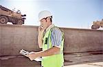 Construction worker foreman talking on cell phone at sunny construction site